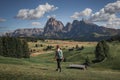 Girl hiking along meadows with wooden cabins at Alpe di Siusi during summer with view to mountains of Plattkofel and Langkofel in Royalty Free Stock Photo