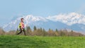Girl hiking in the mountains with spring contrasts of green meadows and snow on the mountains Royalty Free Stock Photo