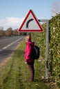 Girl hiking under a curve sign on the road