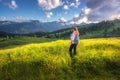 Girl on the hill with yellow flowers and green grass in mountain