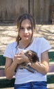 A girl is holding a baby cat in her arms. Children and pets. A teenage girl hugs a cute little kitten sitting on a wooden bench. A Royalty Free Stock Photo