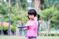A girl holding a badminton racket and a racquet, a child is a insecure expression or embarrassed expression.
