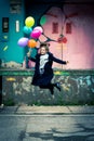 Happy young woman jumping high while holding balloons