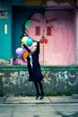 Happy young woman jumping high while holding balloons