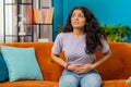 Sick ill woman suffering from period cramps, stomach ache menstrual pain lying on sofa at home room Royalty Free Stock Photo