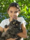 A girl holding a black stray cat in her arms smiles and looks at the camera. Royalty Free Stock Photo
