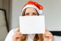 A girl is holding a blank letter to Santa Claus. Woman in a Christmas hat holding a letter in front of her. Mockup Royalty Free Stock Photo