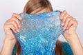 Girl holding blue glitter slime in front of her face Royalty Free Stock Photo