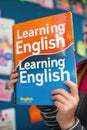 A girl holding a book titled learning english and england, AI