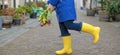 The girl is holding a bouquet of fresh tulips in her hands, yellow and pink in a blue cloak and yellow rubber boots. in a city on Royalty Free Stock Photo