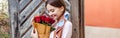 Girl holding bouquet of red roses while standing near old wooden door Royalty Free Stock Photo