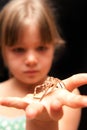 Girl holding brown spider on the palm of her hand