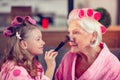 Girl holding brush and putting facepowder on face of granny