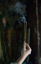 Girl holding burning sticks of incense at the holy buddhist temple