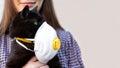 Girl Holding Cat in Hands. Cat wearing medical mask because of Coronavirus or air pollution or virus epidemic in the city. Place Royalty Free Stock Photo