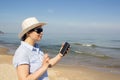 Girl holding a cellphone with sea ocean background. Royalty Free Stock Photo