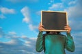 Girl holding chalkboard at face level, against the sky with clouds. Copy space for your text design. billboard, chalk Royalty Free Stock Photo