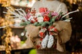 Girl holding a christmas composition with pink orchids, white roses, fir-tree branches, red apple and candle in the Royalty Free Stock Photo