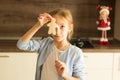 A girl holding a Christmas man biscuit in her hands at face level