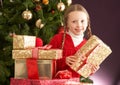 Girl Holding Christmas Present In Front Of Tree Royalty Free Stock Photo