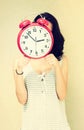 Girl holding clock in front of face. filtered image Royalty Free Stock Photo