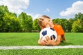 Girl holding close football, smiling and laying