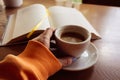 Girl holding coffee cup with open book on background. Cup of coffee and book with bookmark. Cozy morning time. Leisure concept. Royalty Free Stock Photo