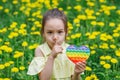 The girl is holding a colorful game of poppit in her hands. The child shows a secret gesture and put his finger to his