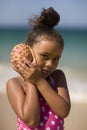 Girl holding conch shell next to her ear. Royalty Free Stock Photo