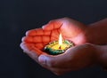 A gril holding lit diya in her hand for celebrating diwali and dhanteras