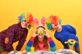 Girl holding Easter eggs in front of her eyes two clown boys are standing side by side Royalty Free Stock Photo