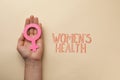 Girl holding female gender sign near text Women`s Health on beige background, top view
