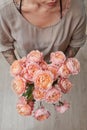 A tender bouquet of pink roses, a woman is holding in hands on a gray wooden background. Top view Royalty Free Stock Photo