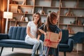 Girl holding gift box behind her. Happy holidays. Young mother with her daughter is together at apartment Royalty Free Stock Photo