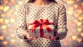 A girl holding a gift box with a red ribbon on a love shaped bokeh effects Royalty Free Stock Photo