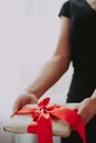 The girl is holding a gift with a red ribbon. A woman in a black dress on a white background is holding a box with red