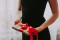 The girl is holding a gift with a red ribbon. A woman in a black dress on a white background is holding a box with red