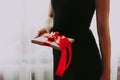 The girl is holding a gift with a red ribbon. A woman in a black dress on a white background is holding a box with red