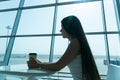 Girl is holding a glass of coffee in airport`s business lounge with aircraft Royalty Free Stock Photo