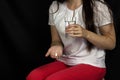 Girl holding a glass of water in her hand and pill in her palm, black background Royalty Free Stock Photo