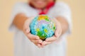 A girl is holding the globe by her hands with yellow background. The concept of saving the world or caring for the world Royalty Free Stock Photo