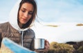 Girl holding in hand cup of drinks, people planning trip in snow mountain, tourist look on map, hipster on background winter