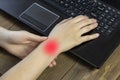 A girl holding hands behind a laptop, a painful hand, arthrosis hand