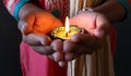 A girl holding a colourful illuminated diya in her hand