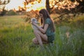 Girl holding a labrador puppy and smiling. At sunset on a forest glade in the spring. Friendship, happiness.