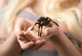 Girl holding a large spider on hands