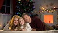 Girl holding letter for Santa, together with parents smiling at camera, Xmas eve