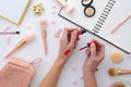 Girl is holding lipstick in hands, makeup swatches,notebook. highlighter,make-up cosmetics on white background. Flat lay Royalty Free Stock Photo