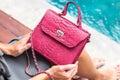 Girl holding luxury snakeskin python handbag on a swimming pool background. Tropical island Bali.