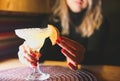 Girl holding margarita cocktail on the table in the restaurant. Alcoholic drinks. Beautiful hands